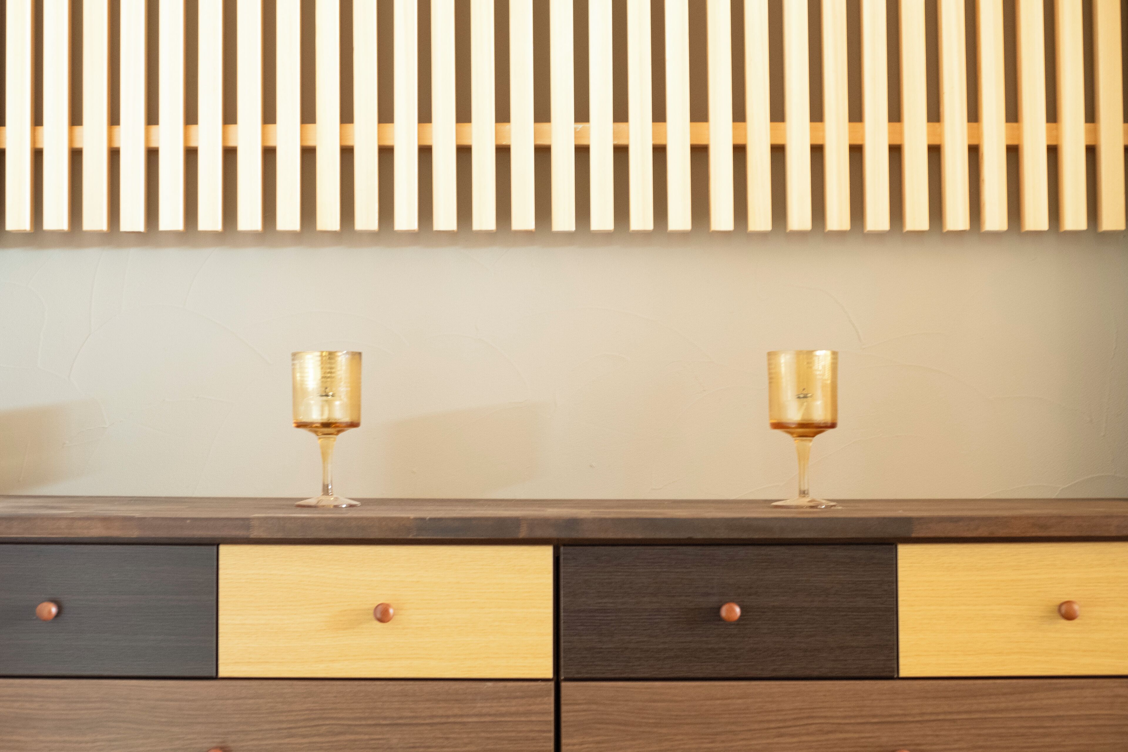 A wooden dresser with two wine glasses on top.
