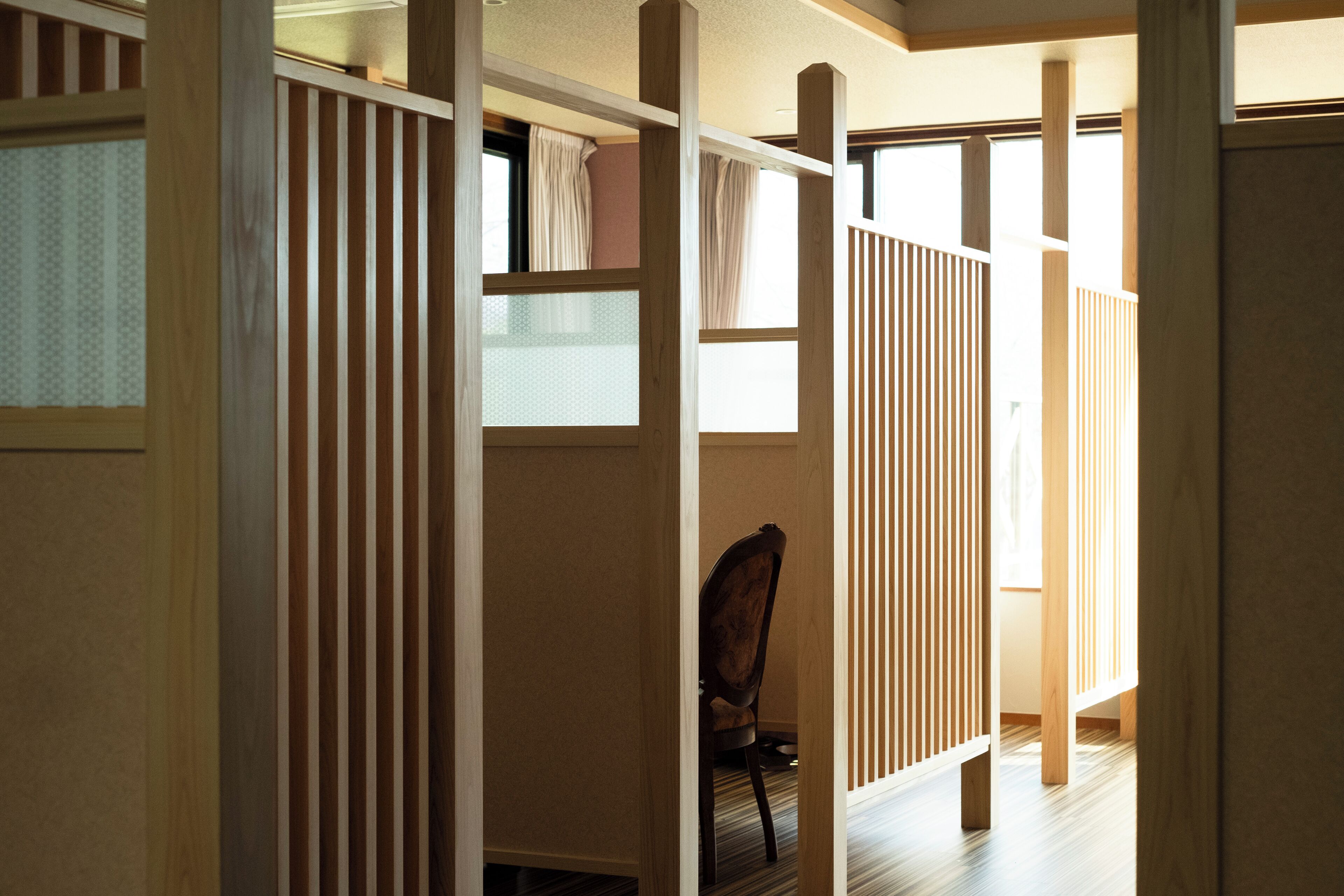 A room with a wooden partition, a chair, and a window.