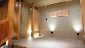 Una habitación con piso de madera, pared de piedra y separador de madera.