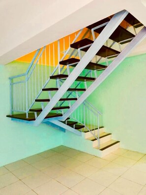 A staircase with a metal railing and wooden steps, leading to a landing with a tiled floor. - Rainbow Covenant 29 (Kota Kinabalu)