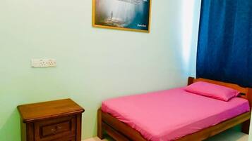 A bedroom with a bed, a nightstand, a wall-mounted light switch, and a framed quote on the wall.