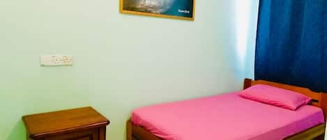 A bedroom with a bed, a nightstand, a wall-mounted light switch, and a framed quote on the wall.
