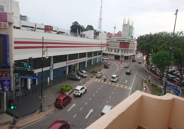 A street view with a bank, a red car, and a white car driving on the road. - Hotel Mill Road (Malacca City)