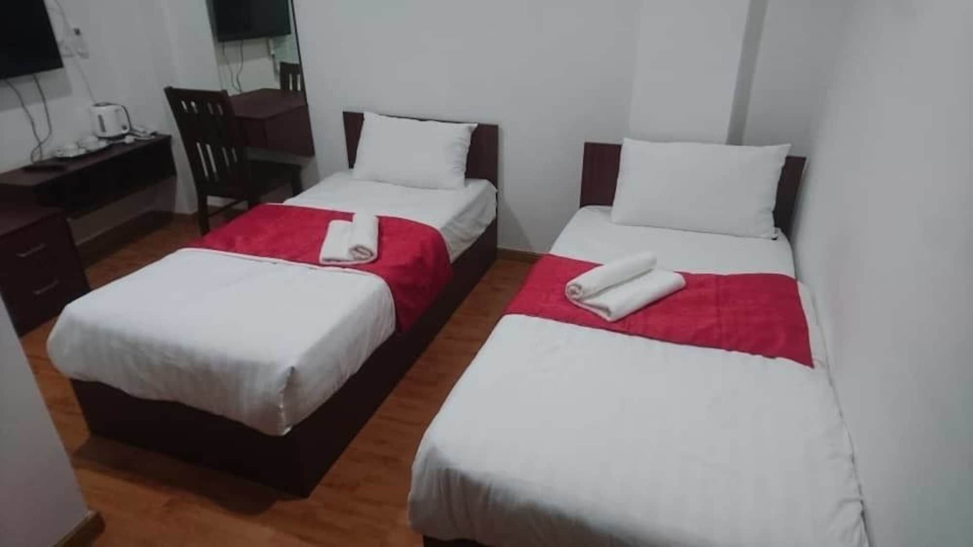 A hotel room with two beds, a desk, and a chair.