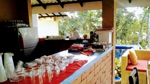 A kitchen area with a brick counter, various kitchen utensils, and a refrigerator.