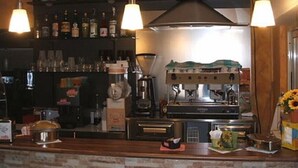 A bar area with a coffee machine, shelves of bottles, and a vase with sunflowers. - Camping Borghetti (Ortona)