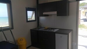 A compact kitchen with a gas stove, a sink, and dark cabinetry. - Camping Borghetti (Ortona)