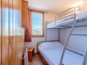 A bunk bed room with a window, wooden walls, and a small wooden stool. - Charming 1-BR Apt in Les Coches - Sleeps 4, Near Slopes (La Plagne)