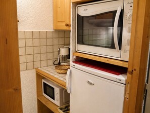 A compact kitchen with a microwave, a coffee maker, and a refrigerator.