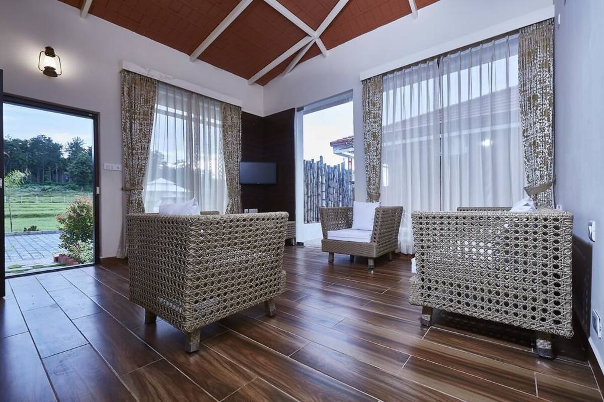 A spacious room with wicker furniture, a flat-screen TV, and large windows offering a view of the outdoors.