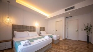 A modern hotel room with a large bed, bedside tables, a bedside lamp, a door, and a potted plant. - Bianco Hotel (Ksamil)