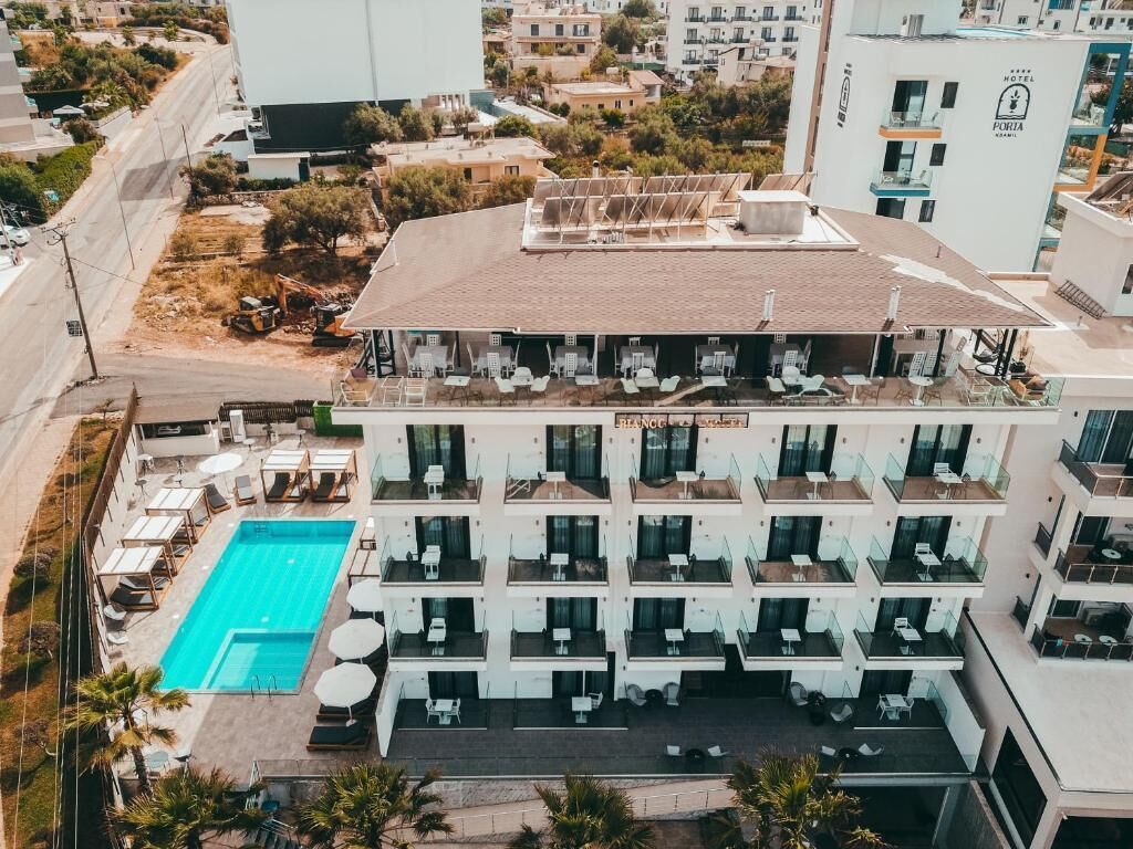 A multi-story hotel with a rooftop pool, balconies with outdoor seating, and a clear view of the surrounding area.