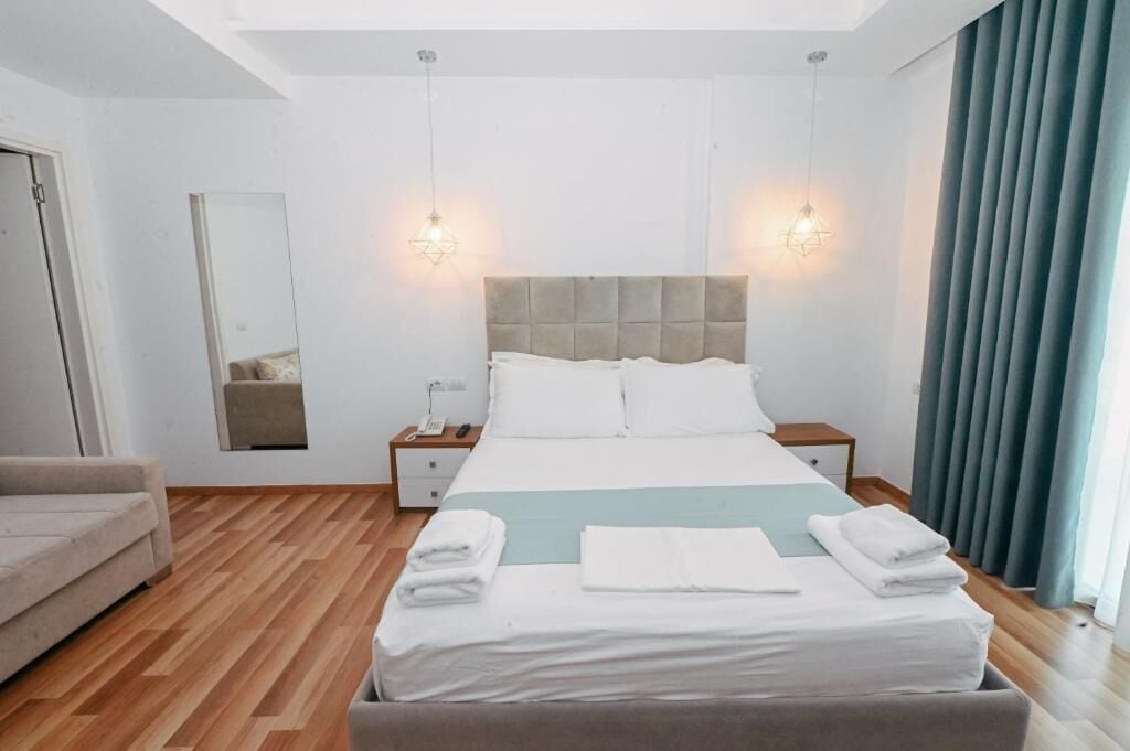 Ein modernes Hotelzimmer mit einem großen Bett, Nachttischen, einem Spiegel und einem Sofa.
