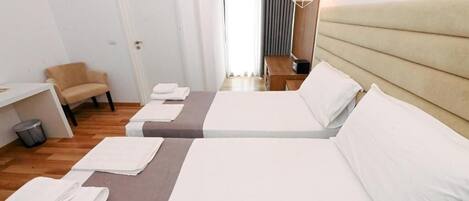 A hotel room with two beds, a chair, a desk, and a hanging light fixture.