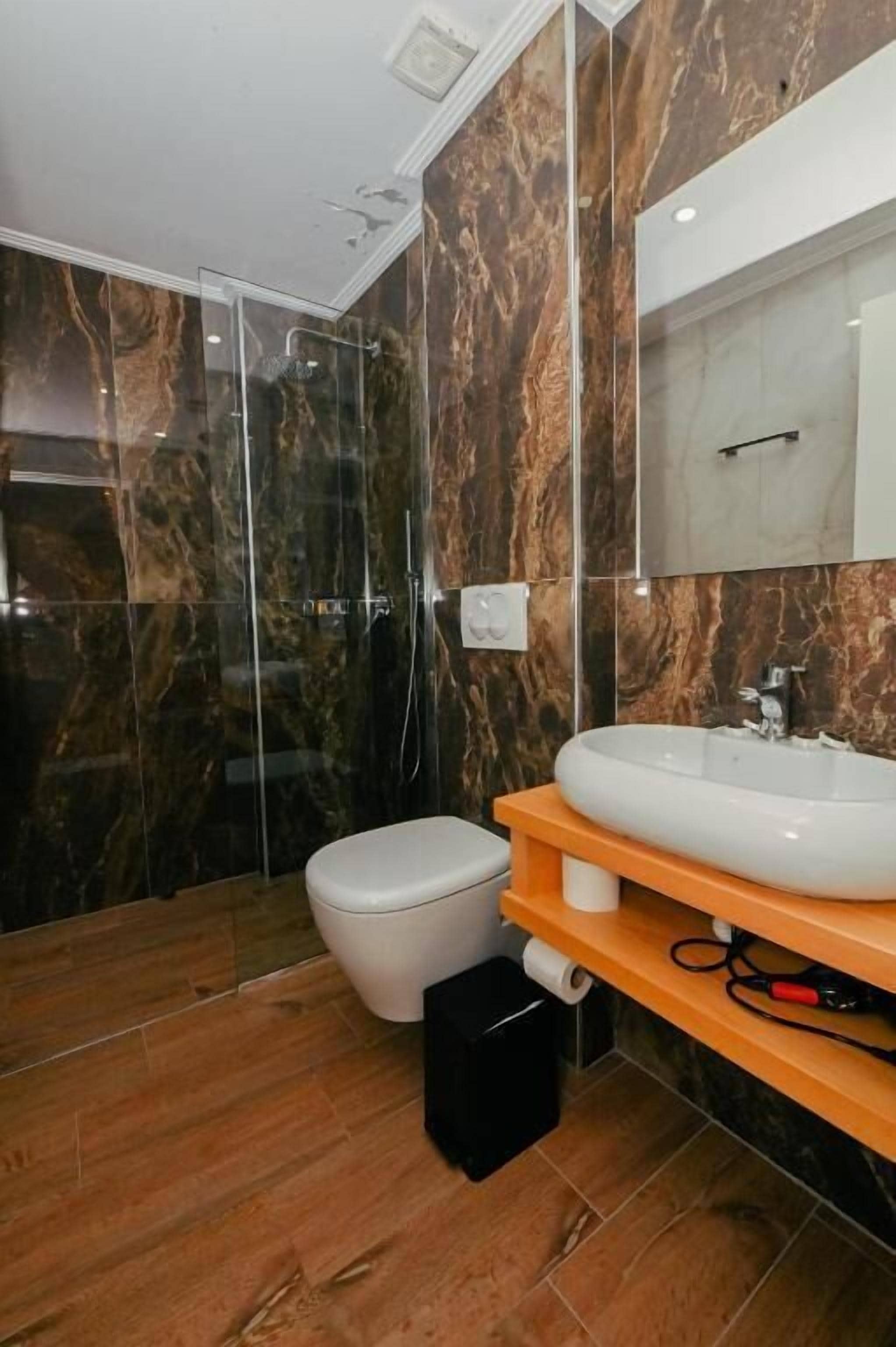 A modern bathroom with a glass shower enclosure, a white toilet, and a marble backsplash.
