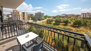 Un balcon avec une table et des chaises, donnant sur un quartier résidentiel avec des immeubles et de la verdure.