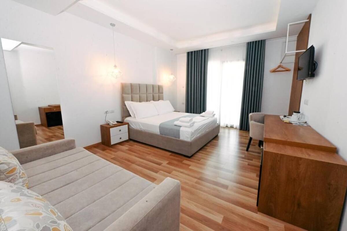 A modern hotel room with a large bed, a desk, and a TV.