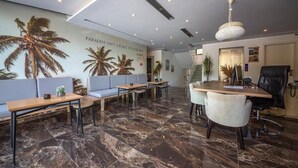 A modern office space with a marble floor, a reception desk, seating area, and a large wall mural. - Bianco Hotel (Ksamil)