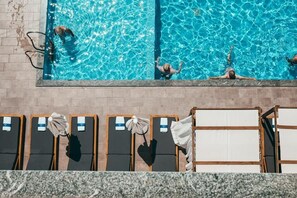 Una piscina al aire libre de temporada, sombrillas, tumbonas