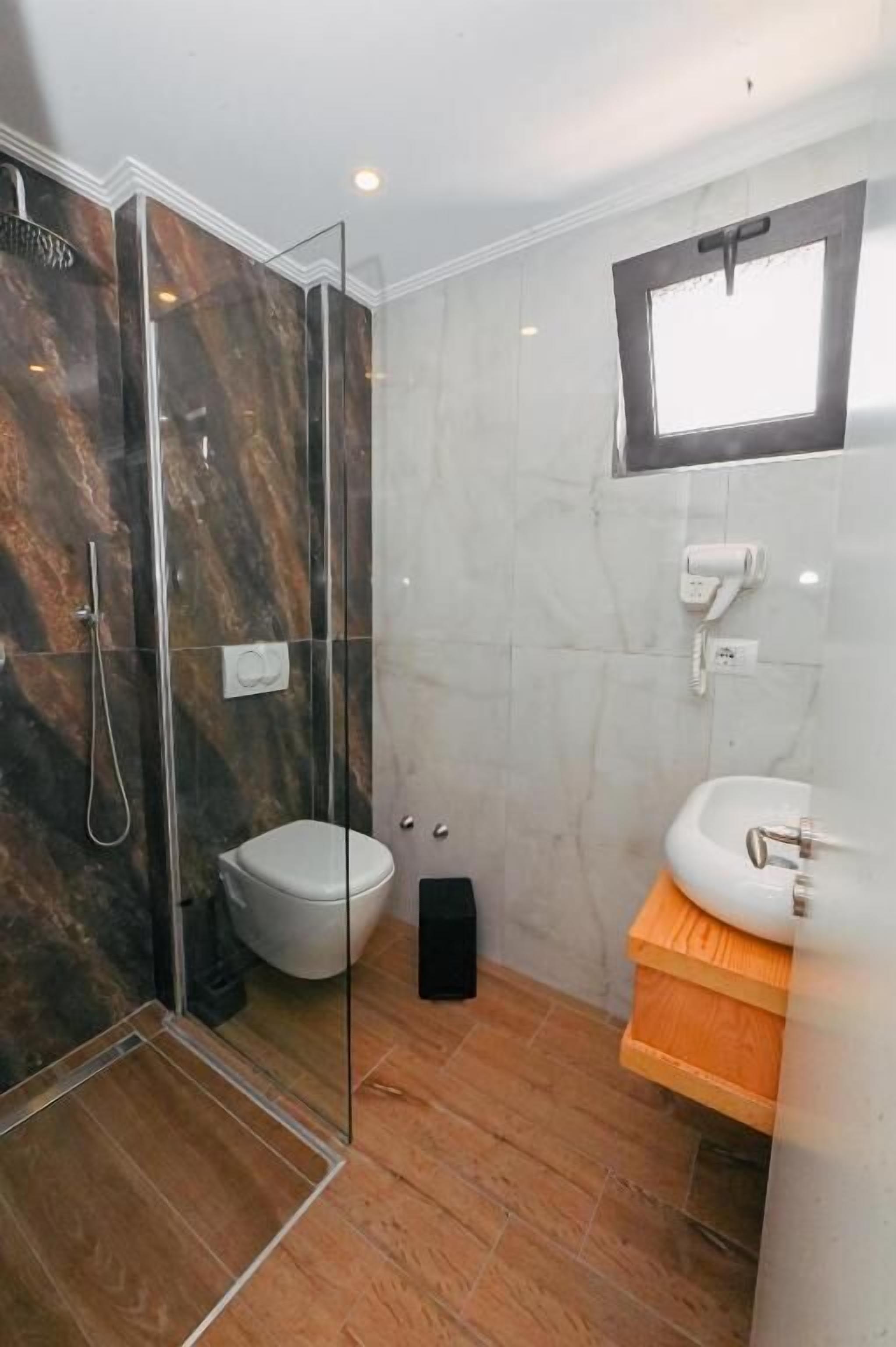 A bathroom with a glass-enclosed shower, a white toilet, and a sink with a wooden countertop.