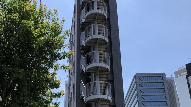 A multi-story building with balconies, a bike parking area, and a clear sky.