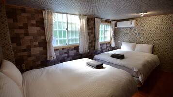 Una habitación de hotel con dos camas, paredes con diseño y una lámpara en el techo.