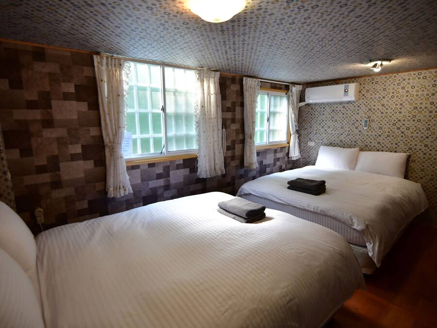 Una habitación de hotel con dos camas, paredes con diseño y una lámpara en el techo.
