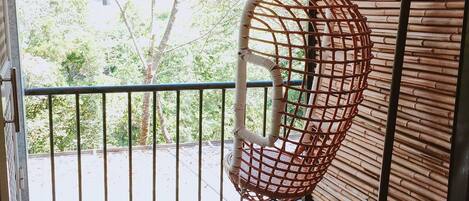 A wooden deck with a hanging chair and a metal railing.