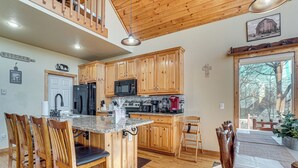 A kitchen with wooden cabinets, a granite countertop, and a dining area with wooden chairs and a table. - Pool, Hot Tub & Mountain Views: Cleveland Cabin (Cleveland)