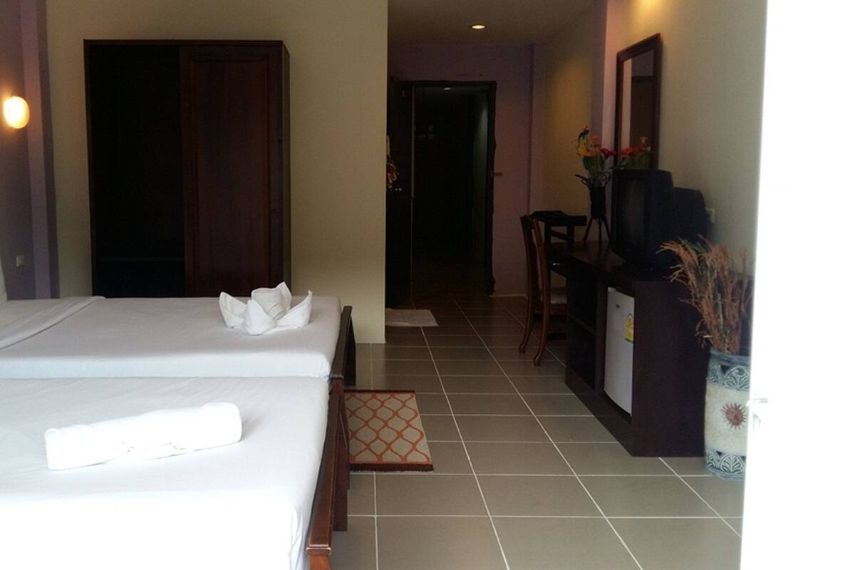 A hotel room with two beds, a desk, a chair, and a television.