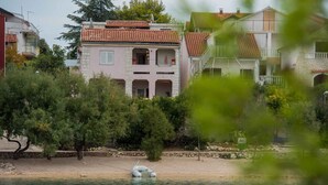 Un edificio costiero con tetto in tegole, un balcone e una piccola barca sulla spiaggia.