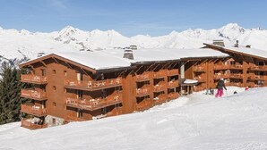 Una cabaña de madera con varios balcones, con vista a una montaña nevada.