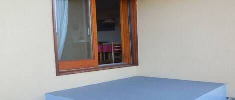 Ein Zimmer mit Fenster, kleinem Balkon und Steinwand.