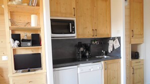 Une cuisine compacte dotée de meubles en bois, d’un four à micro-ondes, d’un lave-vaisselle et d’une machine à café.