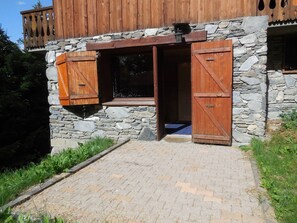 A rustic building with a stone facade, wooden shutters, and a wooden balcony.