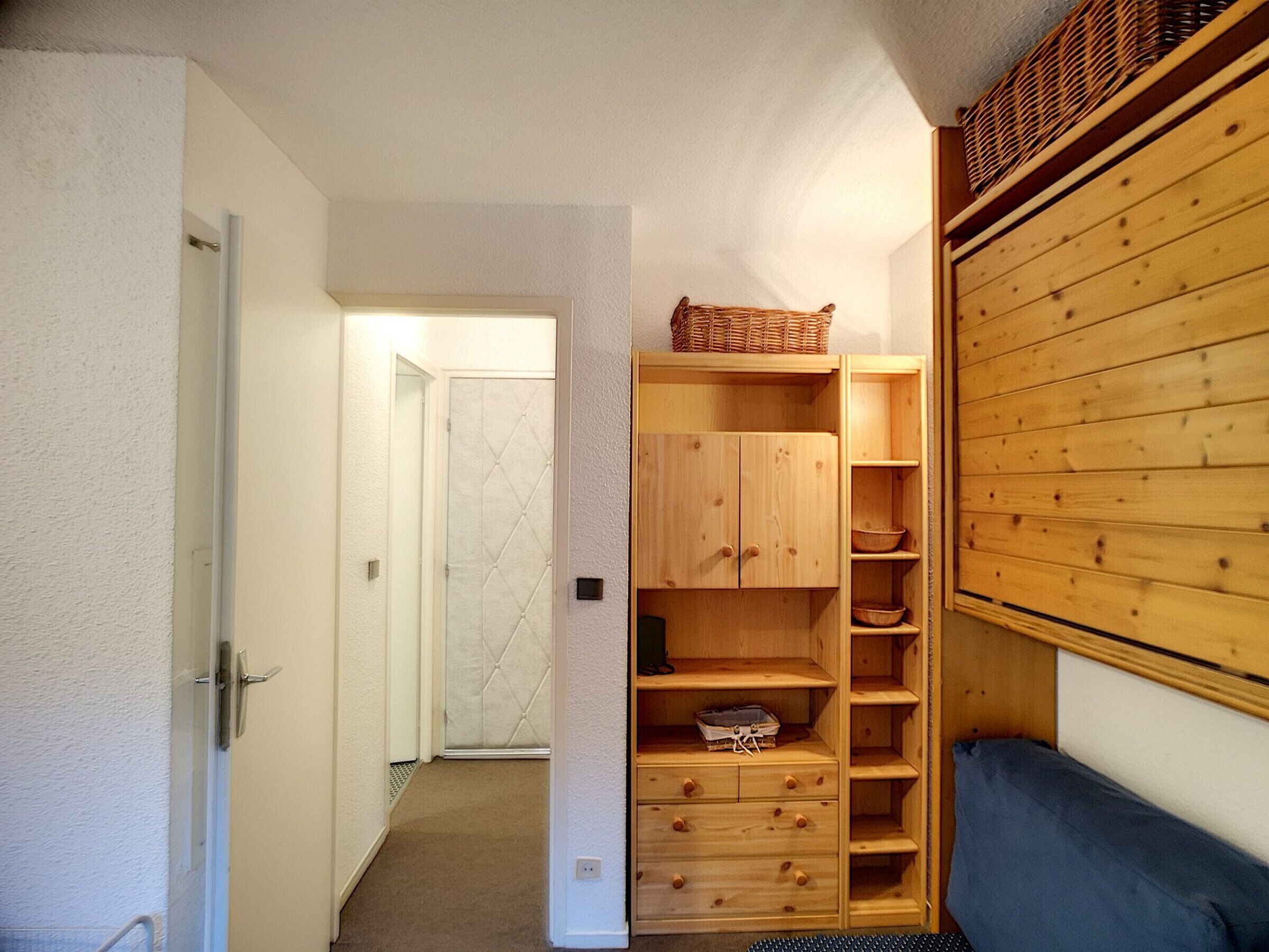 Un couloir avec un meuble en bois, un banc bleu et une porte donnant sur une autre pièce.