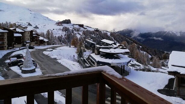A snow-covered mountain village with buildings, a road, and a view of distant mountains. - Cozy studio in Plagne Villages near slopes, balcony, 4 ppl (La Plagne)