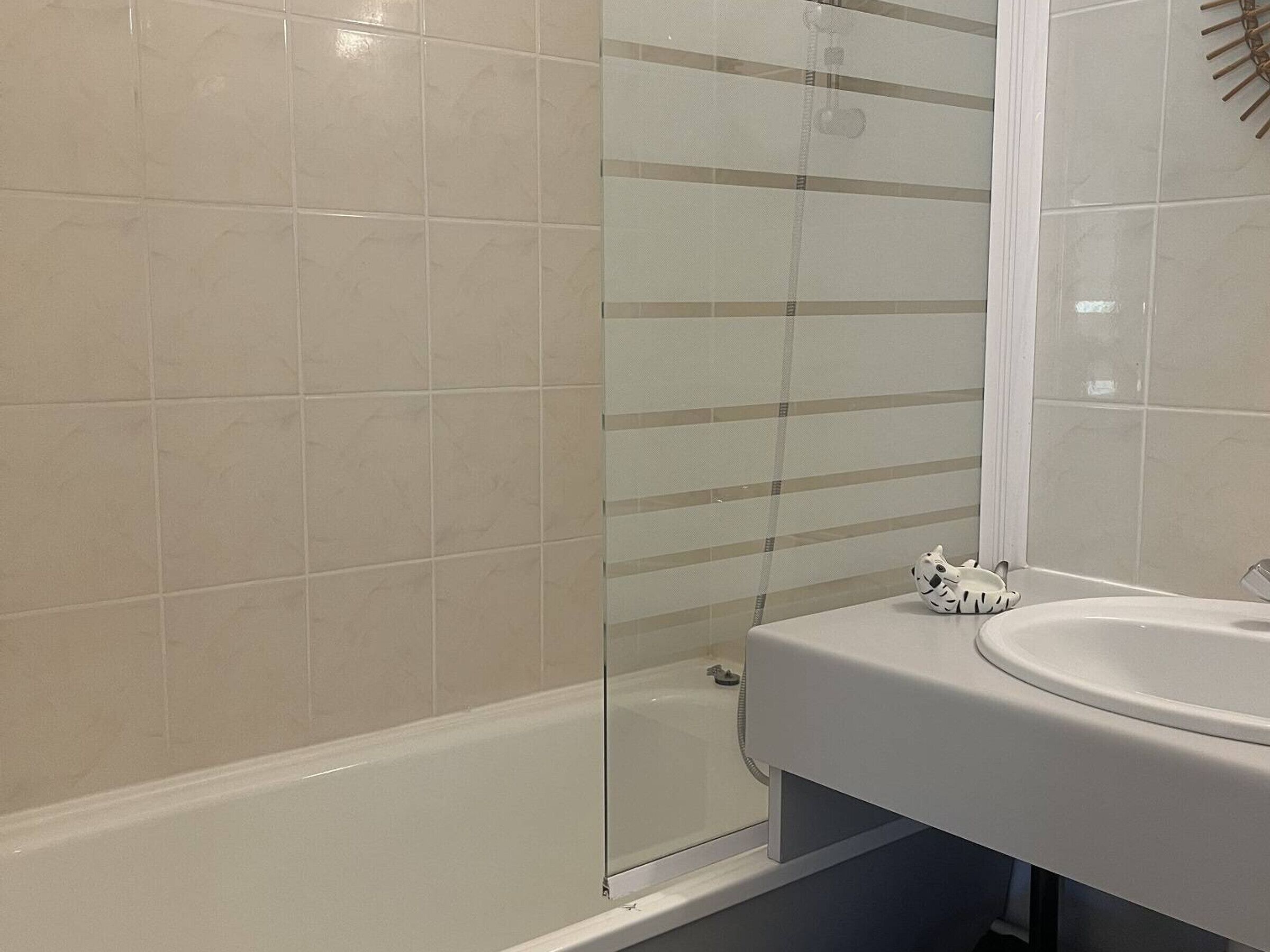 A bathroom with a bathtub, a glass shower enclosure, and a white sink.