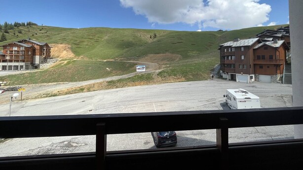 Une vue d’un bâtiment avec un espace de stationnement et une route menant à celui-ci.