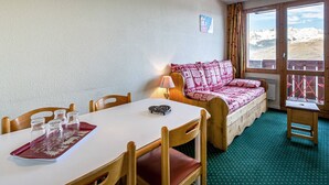 Une pièce chaleureuse comprenant une table à manger, des chaises, un canapé et une fenêtre donnant sur les montagnes.