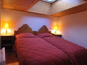 Une chambre avec deux lits, des têtes de lit en bois et des lampes de chevet.