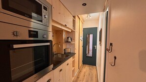 A compact kitchen with a built-in microwave, oven, and sink. - Cozy studio for 2, terrace, pets allowed (La Plagne)