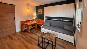 A compact living space with a wooden dining table, a sofa, and a small side table. - Cozy studio for 2, terrace, pets allowed (La Plagne)