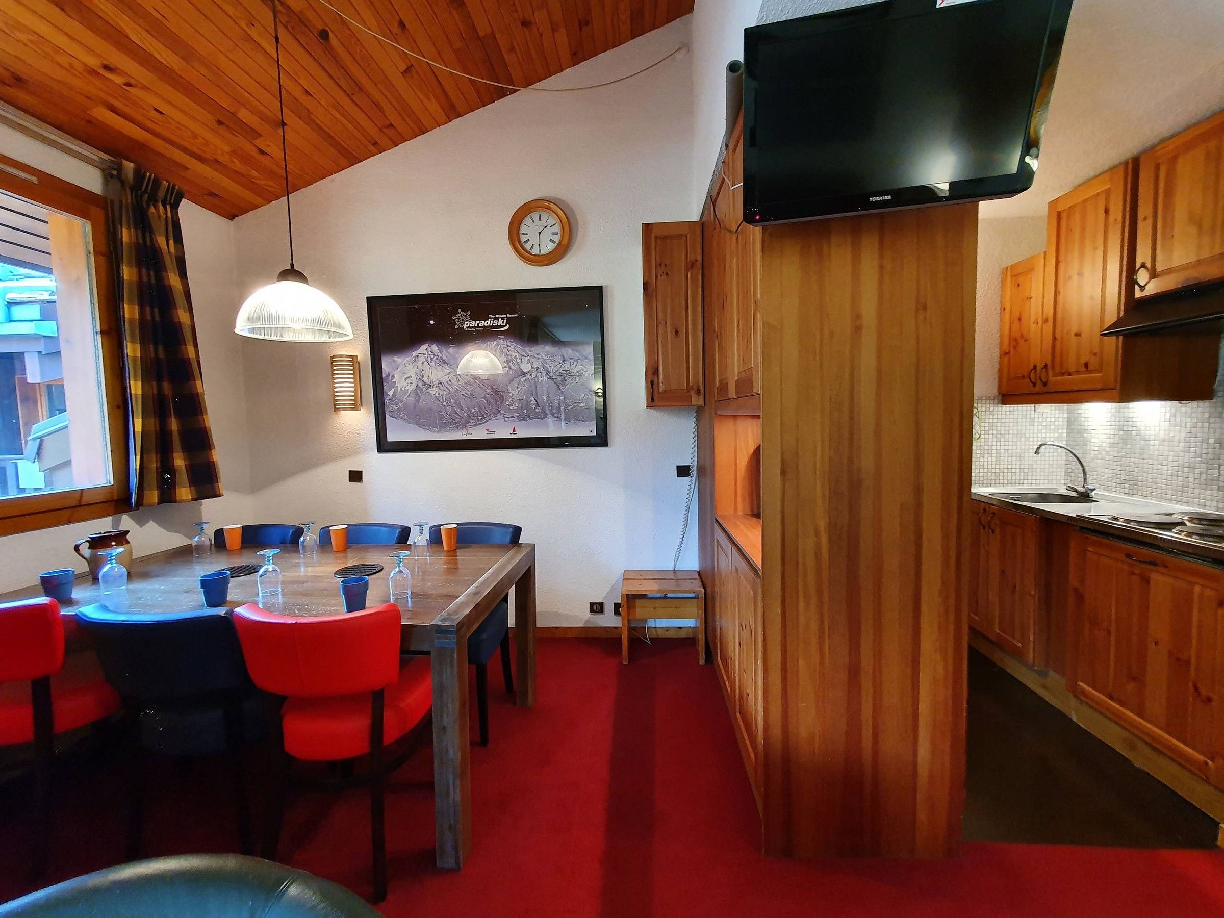 A compact kitchen with wooden cabinets, a built-in microwave, and a red carpeted floor.