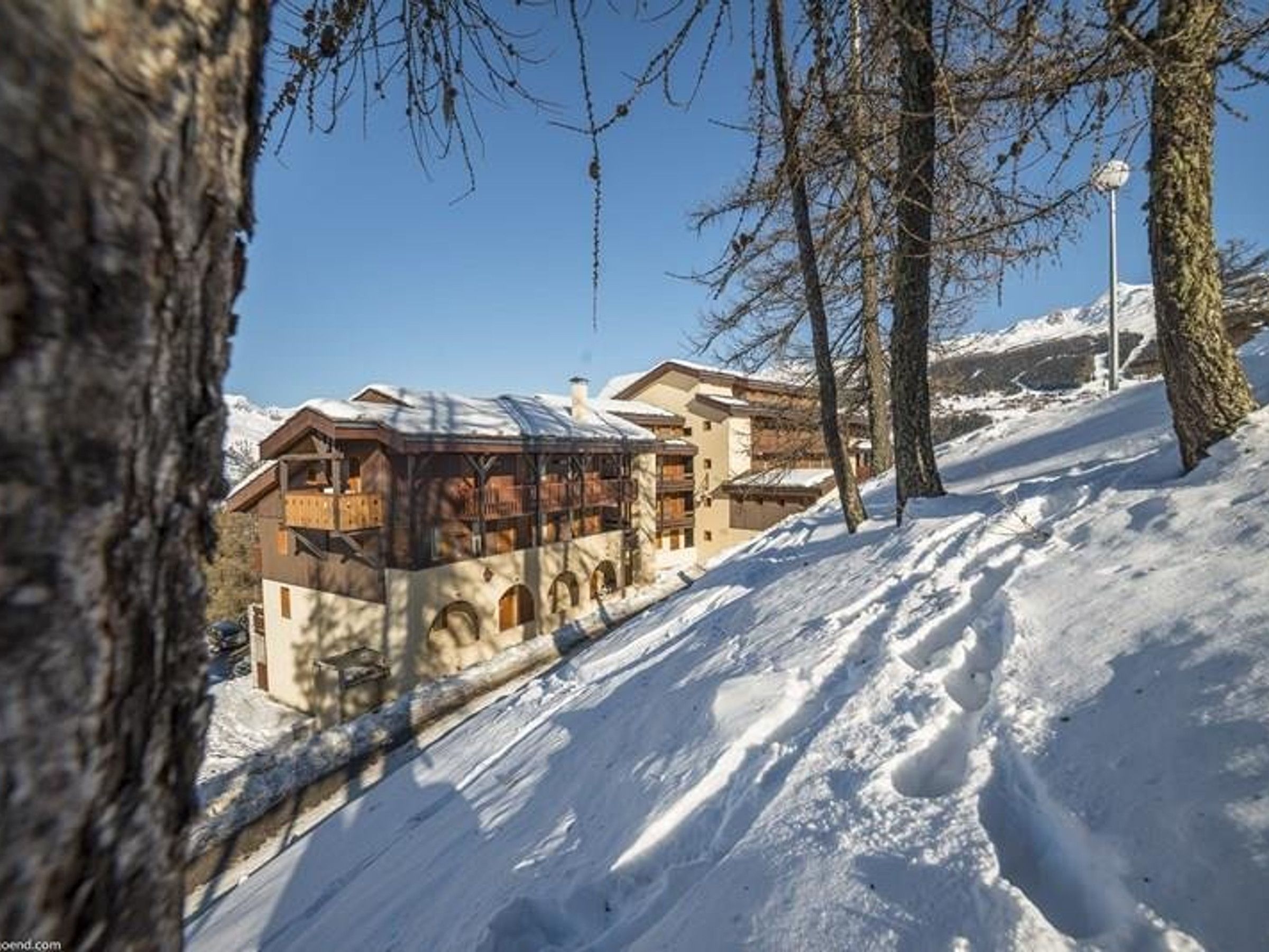 A snow-covered mountain lodge with a wooden exterior and multiple balconies.