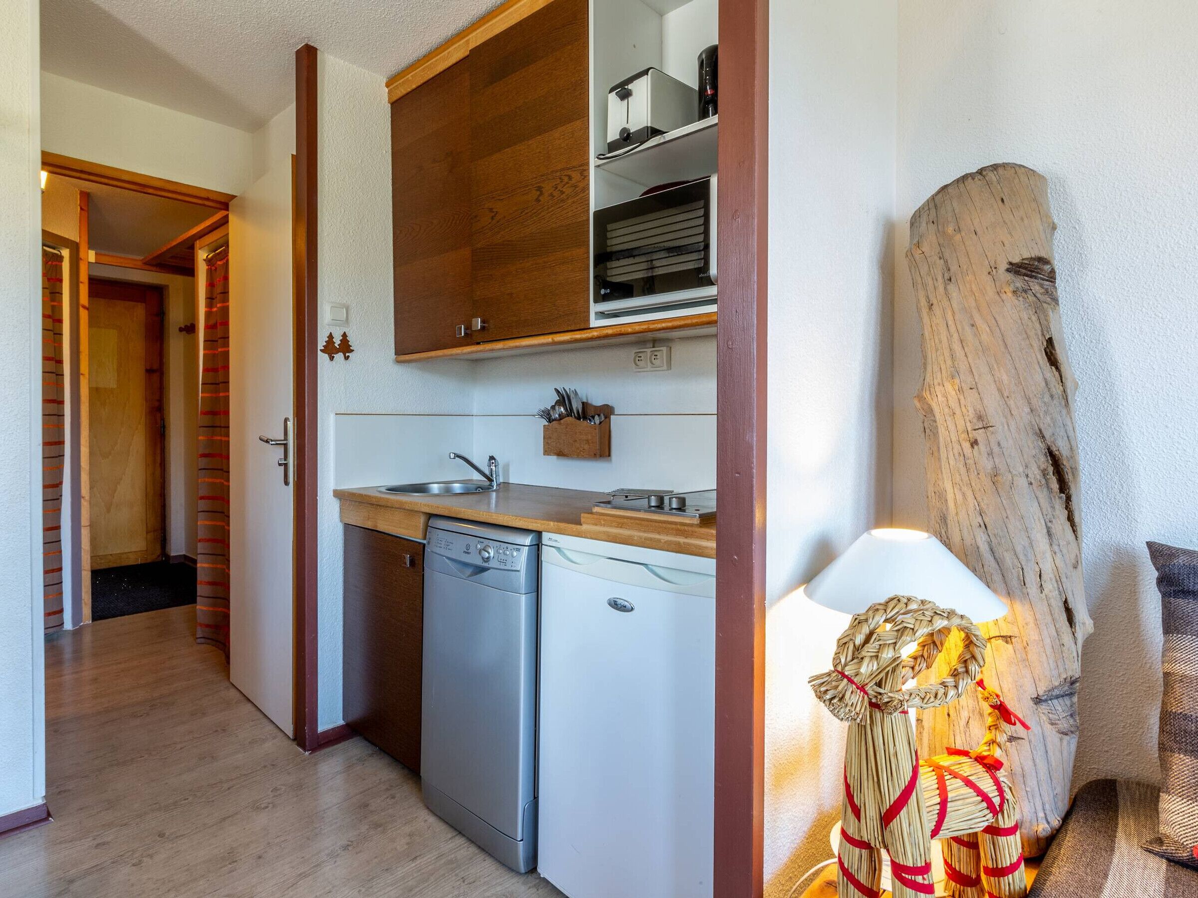 A compact kitchen with a dishwasher, a sink, and a wooden countertop.