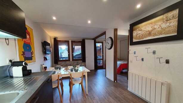 A compact kitchen with a dining area, wooden flooring, and a view through the windows.