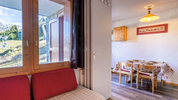 Una habitación acogedora con un banco de madera, una mesa de comedor con sillas y vistas a un paisaje montañoso a través de una ventana.