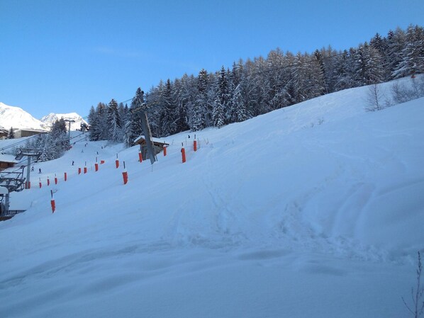 A snow-covered ski slope with a ski lift and a small lodge. - Divisible studio for 4, direct slope access (La Plagne)
