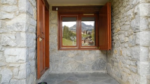 Una habitación con paredes de piedra, una ventana y contraventanas de madera.